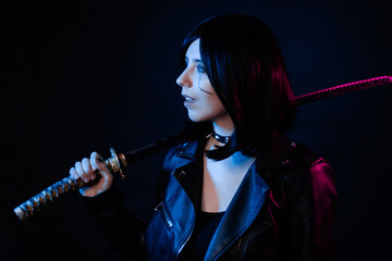 Portrait of a young woman with a bob hairstyle in a black leather jacket with a katana in her hands...