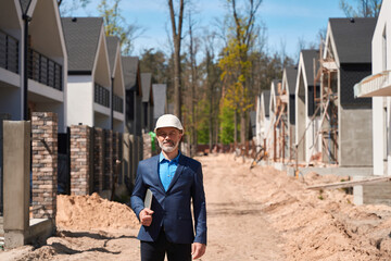 Business man housing developer in hardhat standing at construction site