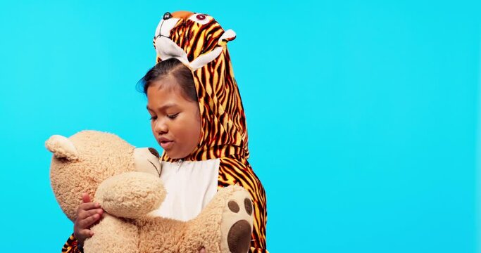 Kids, teddy bear and pajamas with a girl at bedtime on a blue background in studio for imagination. Children, fantasy and a playful young female child in a leopard costume holding a stuffed animal