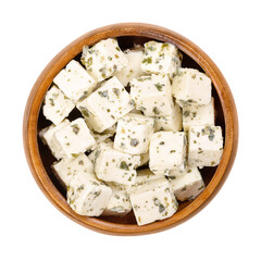 Greek feta cubes, brined cheese with Mediterranean herbs, in a wooden bowl. Cheese, matured in brine, with soft and moist texture, and fresh, salty and acidic taste, cut into cubes, added with herbs.