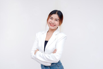 A happy and beaming young woman looking and smiling at the camera with arms crossed. Isolated on a...