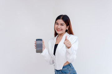 A happy and smiling young woman posing with a smart phone in her hand while holding a thumbs up. Isolated on a white background.