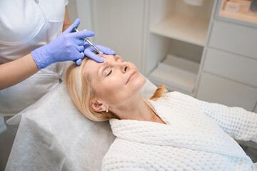Obraz na płótnie Canvas Adult woman getting face injection in beauty salon