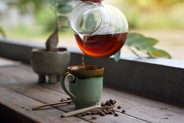 Holding a glass carafe, pour the black drip coffee into the cup and serve it in the morning. Coffee has a special aroma and taste that is unique to each type of coffee.