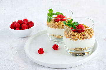 yoghurt with granola in drinking glass decorated with garden raspberry