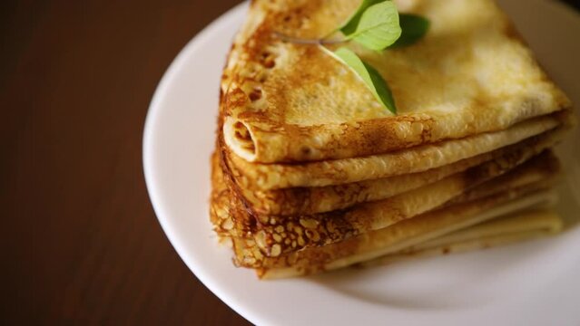 lot of thin pancakes in a plate, on wooden table.
