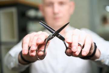 Barber man holds special professional scissors in his hands