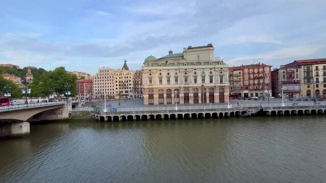 Nervion river and arriaga theater surrounded by buildings from Arenal bridge on sunny day in Bilbao city