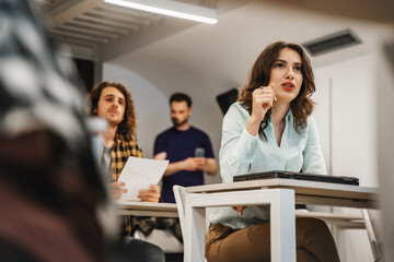 Lovely female junior employee asking a question while having a presentation at the classroom