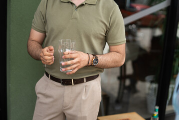 Cropped photo of businessman with watch on his hand holding a glass of water