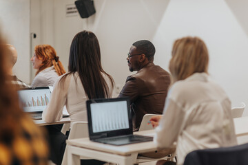 Multiracial business employees discussing graph charts while sitting and working in modern classroom