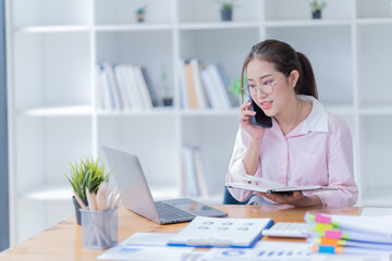 Fototapeta premium Image of smiling beautiful woman writing down notes while sitting at table in office