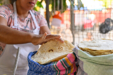 Woman putting hot baked tortilla