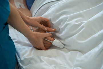 Medic using pulse oximeter with the hospitalized patient in hospital