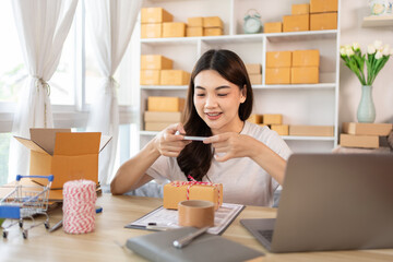 Asian Entrepreneur Working from Home, Capturing Identity Verification and Product Shipping on Mobile Phone, Working at Home: Online Store Management and Package Delivery for SMEs and Entrepreneurs.