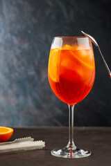Aperol spritz cocktail and steel bar tools on dark background. Cocktail Aperol Spritz and an orange slice. Copy space