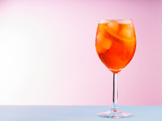 Cocktail Aperol Spritz with orange slice and ice cubes. Aperol Spritz cocktail in glass on a pink...