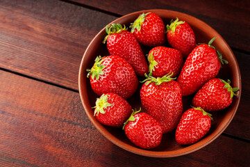 Fresh strawberries in plate on wooden table. Top view. Copy space