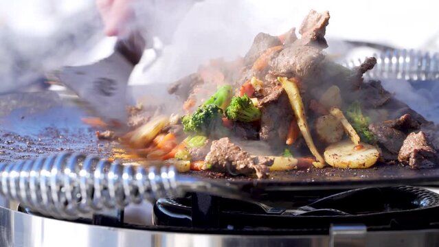 Stir-fried Reindeer meat Mix being prepared Outside with Friends on a Gas burner Murrikka griddle pan in Northern Sweden Winter. Close up Grill footage.