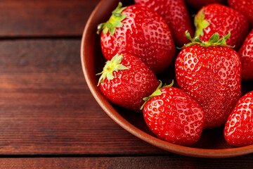 Fresh strawberries in plate on wooden table. Top view. Copy space
