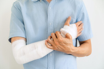 Obraz na płótnie Canvas Young man with gauze bandage wrapped around injury hand on white background