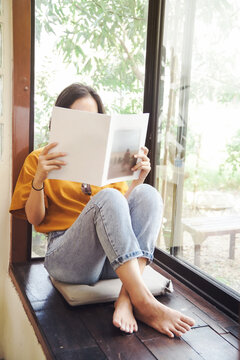 Close Up Teenage Girl Holding And Reading Book Or Magazine  In Reading Room At Home, Copy Space Concept.