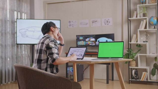 Side View Of Asian Male Yawning While Drawing Car Concept On Tablet Beside Green Screen Laptop In The Studio With Tv And Computers Display 3D Electric Car Model 
