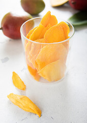 Fototapeta na wymiar Sweet dried mango slices with fresh raw fruits on light background.