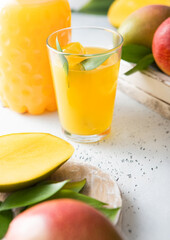 Fresh mango juice and glass with ice cubes and fresh raw fruits.