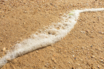 white sea foam on a sandy beach