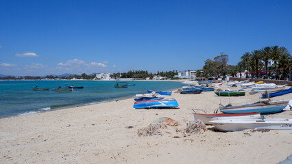 View of the coast in Tunisia, small boats on the beach, blue clear sky and azure sea, boats on the beach in Tunisia