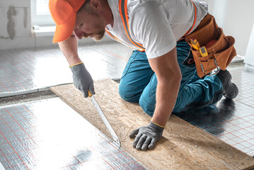 Work on underfloor heating. Trimming of a underfloor heating insulation using a special knife....