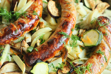 Close-up roasted vegetables and sausages with greens