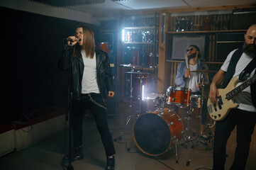 Male singer practice singing on microphone while training with his rock band