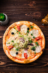 Pizza with cheese, chicken fillet, tomatoes, olives, lettuce and microgreens, Italian food.