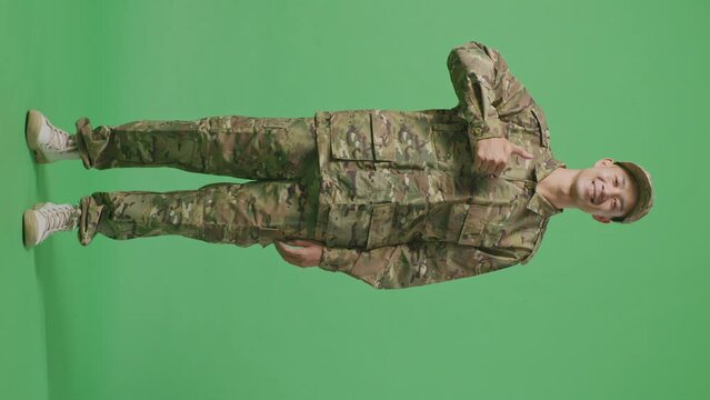 Full Body Of Asian Man Soldier Smiling And Showing Thumbs Up Gesture While Standing In The Green Screen Background Studio
