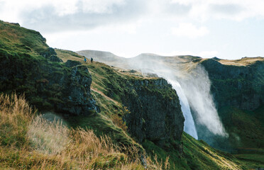 Fototapeta na wymiar Eine von Islands berühmtesten Wasserfällen, umhüllt von Grün (Seljalandsfoss)