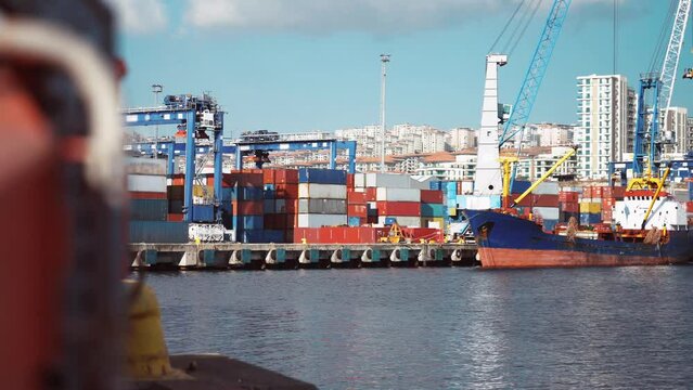 4K footage of port in daylight. Calm sea, docked freight ship, containers and urban landscape stock video.