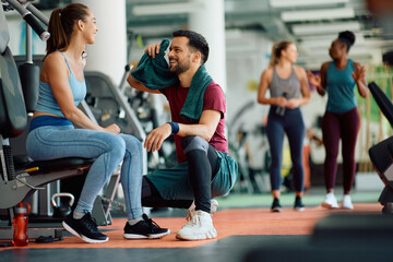 Obraz premium Happy friends talk while taking break from exercising in gym.