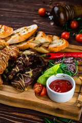 Snacks chicken, beef and pork fillet with potato wedges, onions, lettuce, chili peppers, cherry tomatoes and sauce.