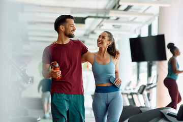 Happy embraced athletic couple in gym after sports training.