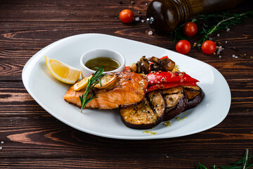Grilled salmon fillet with eggplant, zucchini, mushrooms, sweet peppers, lemon, rosemary and sauce, dinner.