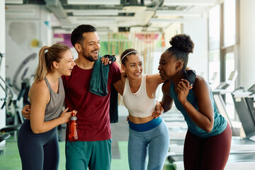 Young cheerful athletes embracing while supporting each other after working out in gym.