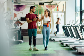 Happy athletic couple talk while walking through gym.