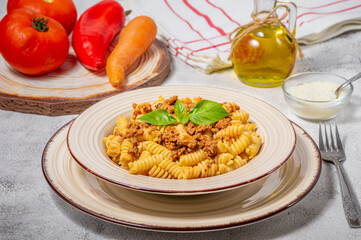 Fusilli pasta with minced meat, tomato sauce, cheese and basil