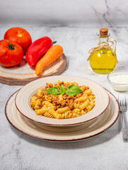 Fusilli pasta with minced meat, tomato sauce, cheese and basil