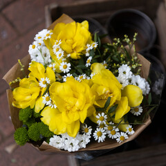 Bouquet in craft paper of white daisies and yellow terry tulips