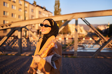 A hijab woman in stylish sunglasses and an elegant French outfit, walking through the city at...
