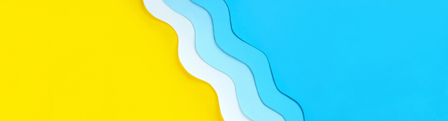 Seashore diagonal long banner with copy space. Summer holidays background with yellow beach sand and paper cut out blue waves. Relaxation on vacations. The ocean coast layout.