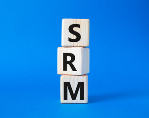 SRM - Sustainability Risk Management symbol. Wooden cubes with word SRM. Beautiful blue background. Business and Finace and SRM concept. Copy space.